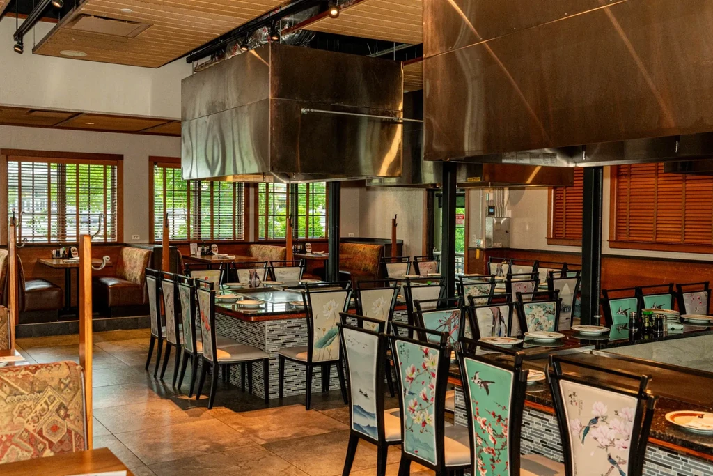 Unoccupied teppanyaki restaurant dining area with grill tables and booths.