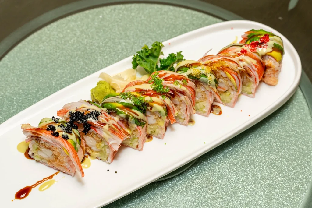 Intricate sushi roll topped with crab, avocado, and colorful fish roe.