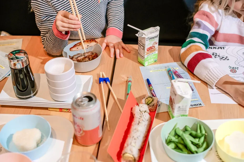 Two people eating Asian food and coloring at a family restaurant table.