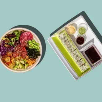 Colorful poke bowl and sushi roll with assorted takeout condiments.