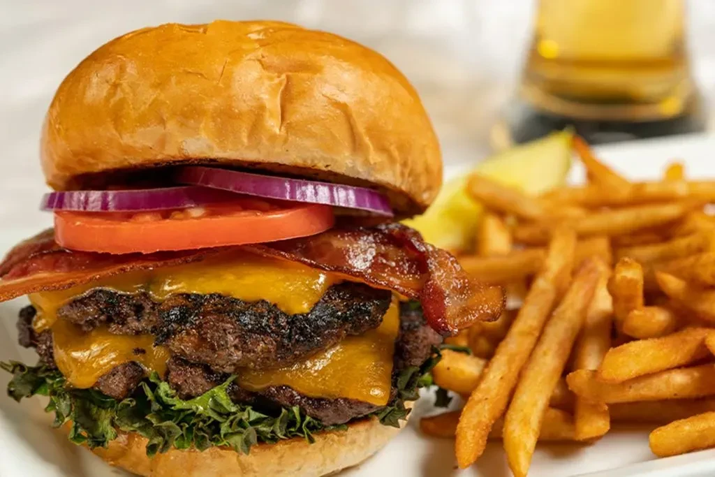 Double cheeseburger with bacon, melted cheese, fries, and lime.