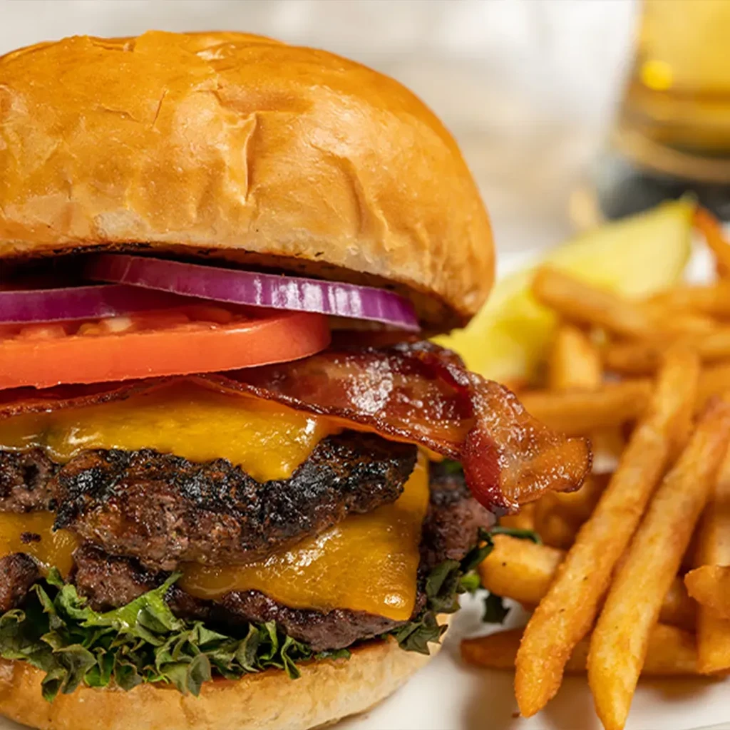 Double bacon cheeseburger with fries, beverage, and lemon wedges.
