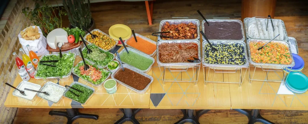 Overhead view of a catered buffet with Mexican food, toppings, and beverages.