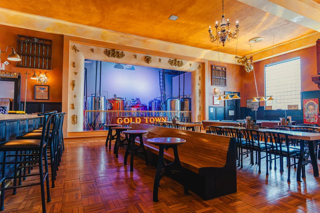 Ornate brewpub interior with diverse seating and visible brewery tanks.