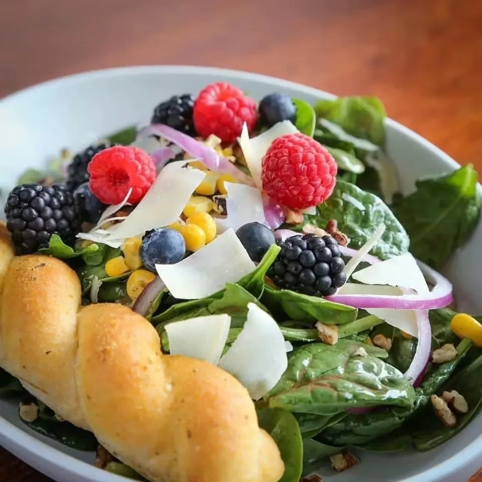 Vibrant berry and spinach salad with cheese, corn, and nuts.