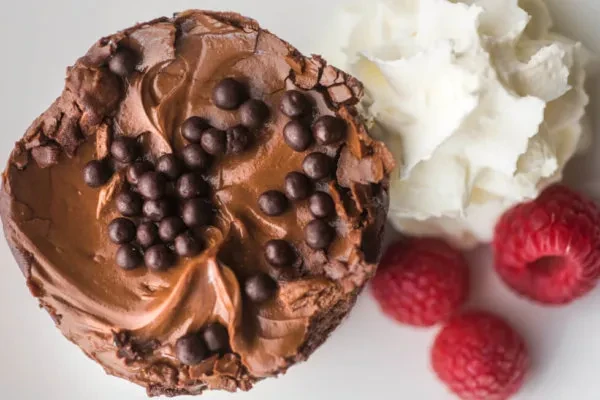Overhead view: Chocolate dessert with pearls, whipped cream, and raspberries.