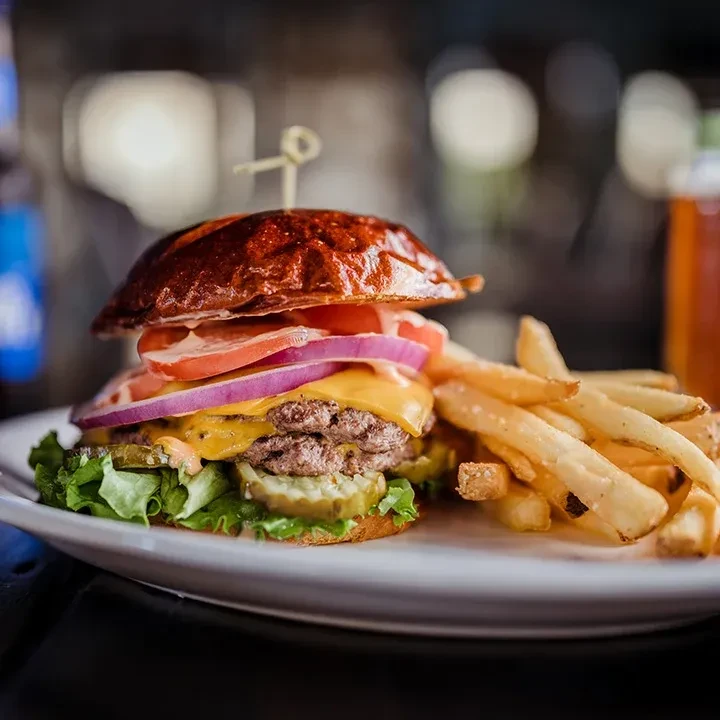 Double cheeseburger with melted cheese, vegetables, and golden french fries.