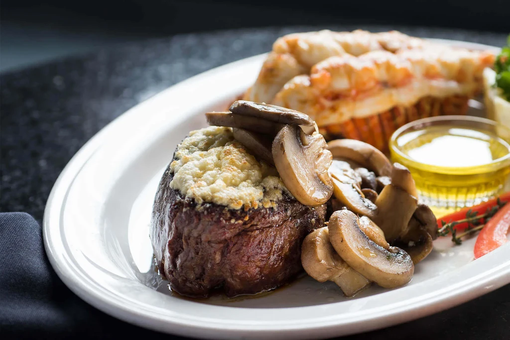 Steak with crumbled topping, mushrooms, lobster, and butter.