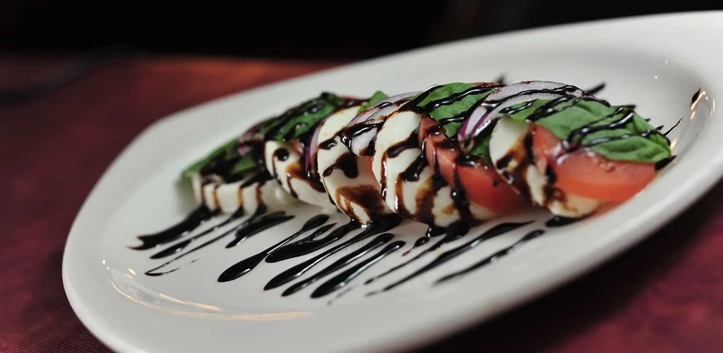 Stacked Caprese salad with mozzarella, tomato, basil, and balsamic glaze.