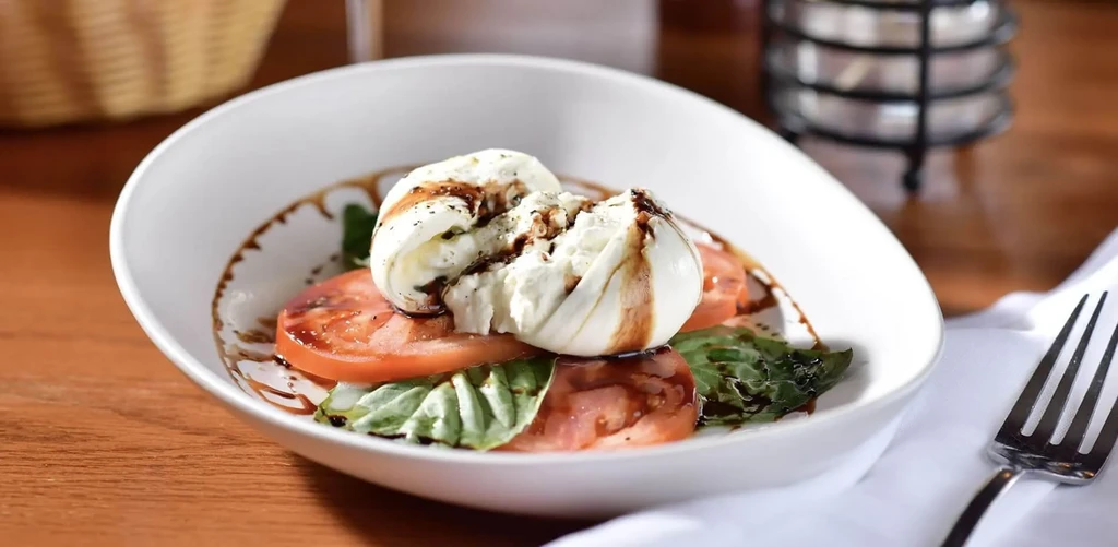Burrata salad with sliced tomatoes, fresh basil, and balsamic glaze.