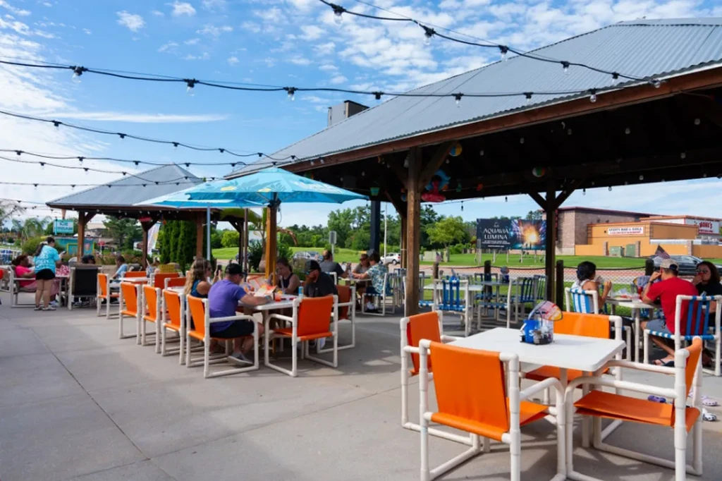 Lively outdoor restaurant patio with dining people on a sunny day.