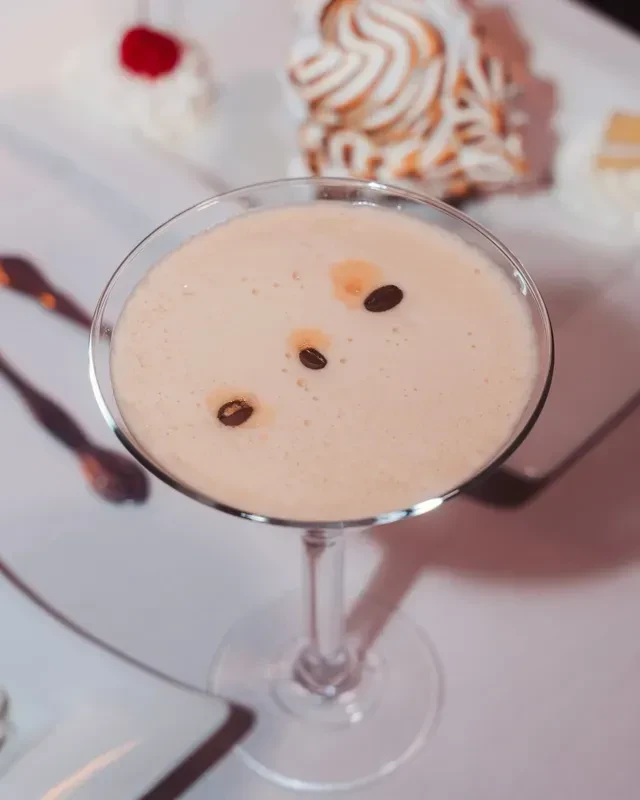 Creamy light-brown cocktail with coffee beans in a martini glass.