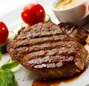 Grilled steak with tomatoes, cucumber, basil, and yellow sauce.