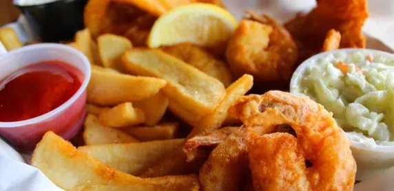 Basket of fried seafood, fries, lemon, ketchup, and coleslaw.