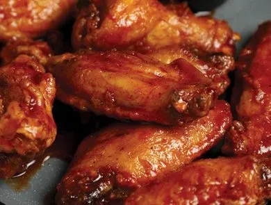 Close-up of glossy, reddish-brown chicken wings with caramelized bits.
