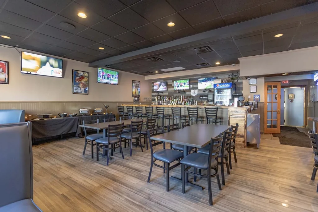 Sports bar interior showing dining area, buffet, and well-stocked bar.