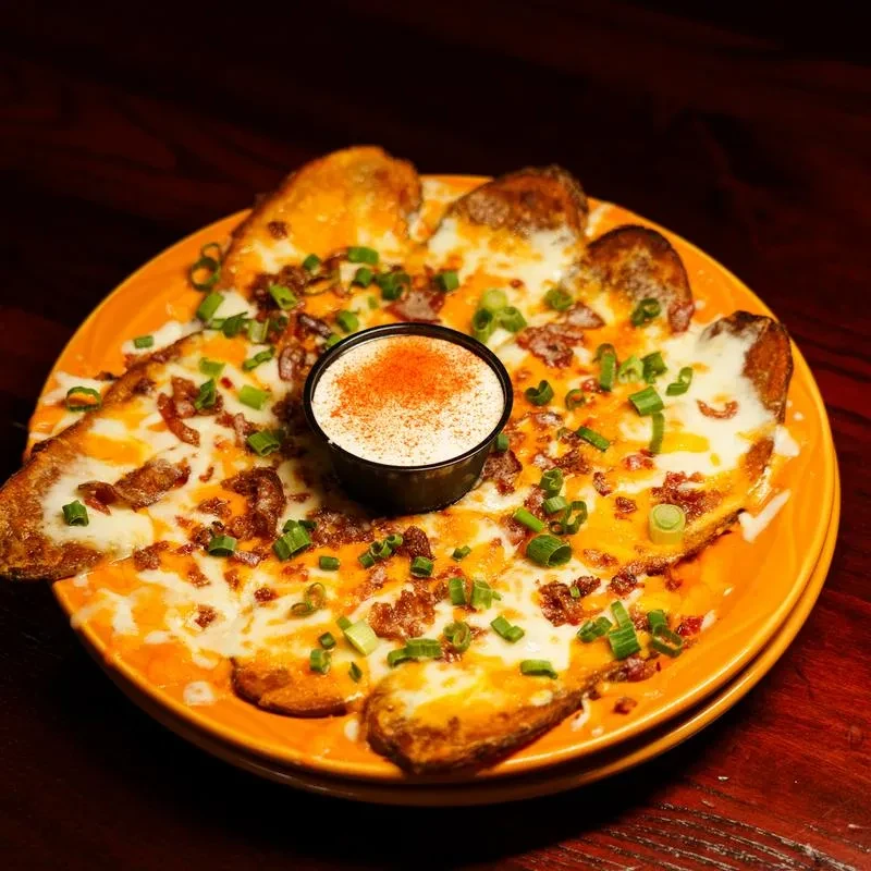 Cheesy potato skins with bacon, green onions, and a sour cream dip.