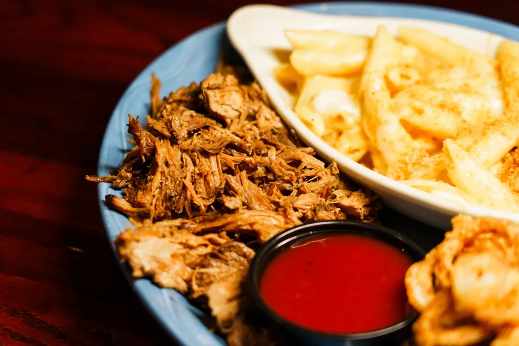 Pulled meat, macaroni and cheese, red sauce, and fried side.