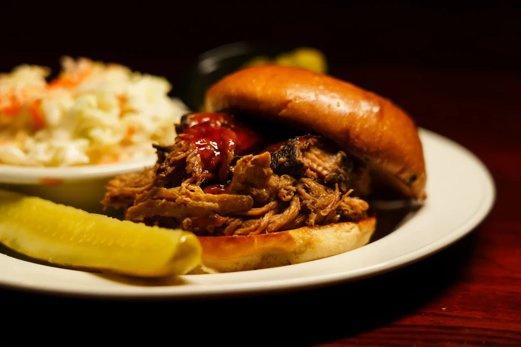 Saucy pulled pork sandwich with dill pickle and coleslaw.