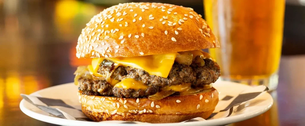 Double cheeseburger with melted cheese and caramelized onions on a plate.