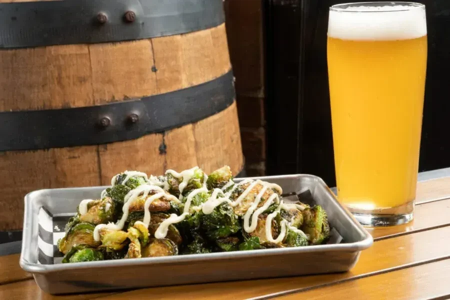 Roasted Brussels sprouts with white sauce and a glass of amber beer.