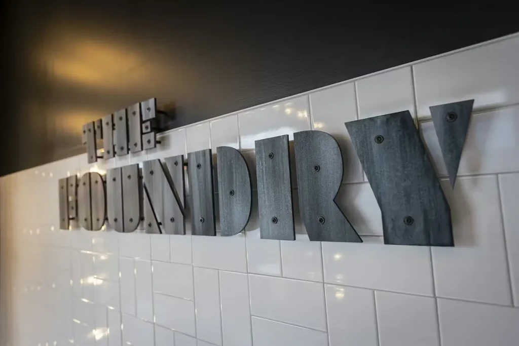 Dark, textured 'THE FOUNDRY' sign on a white subway tile wall.