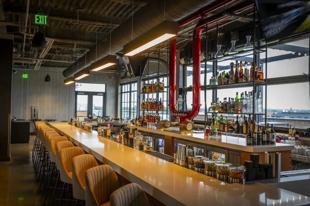 Empty, modern bar with liquor bottles and a unique red beer tap.