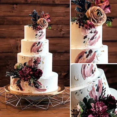 Four-tiered white cake with brushstroke art, colorful flowers, on a gold stand.