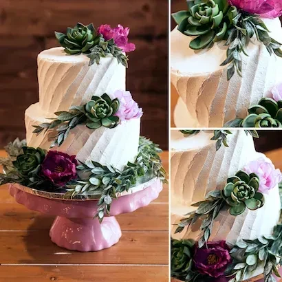 White two-tiered cake with ridged frosting, green succulents, pink and purple flowers.