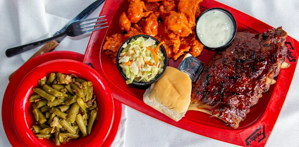Fricker's meal with ribs, chicken, coleslaw, roll, and green beans.
