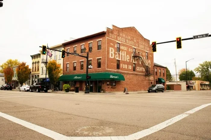 Historic brick corner building, Harrison's awning, faded vintage wall advertisements.