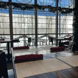 Restaurant dining room with large windows, snowy view, and green garlands.