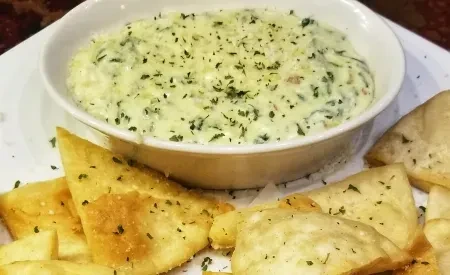 Creamy green spinach dip with herbs and seasoned pita bread.