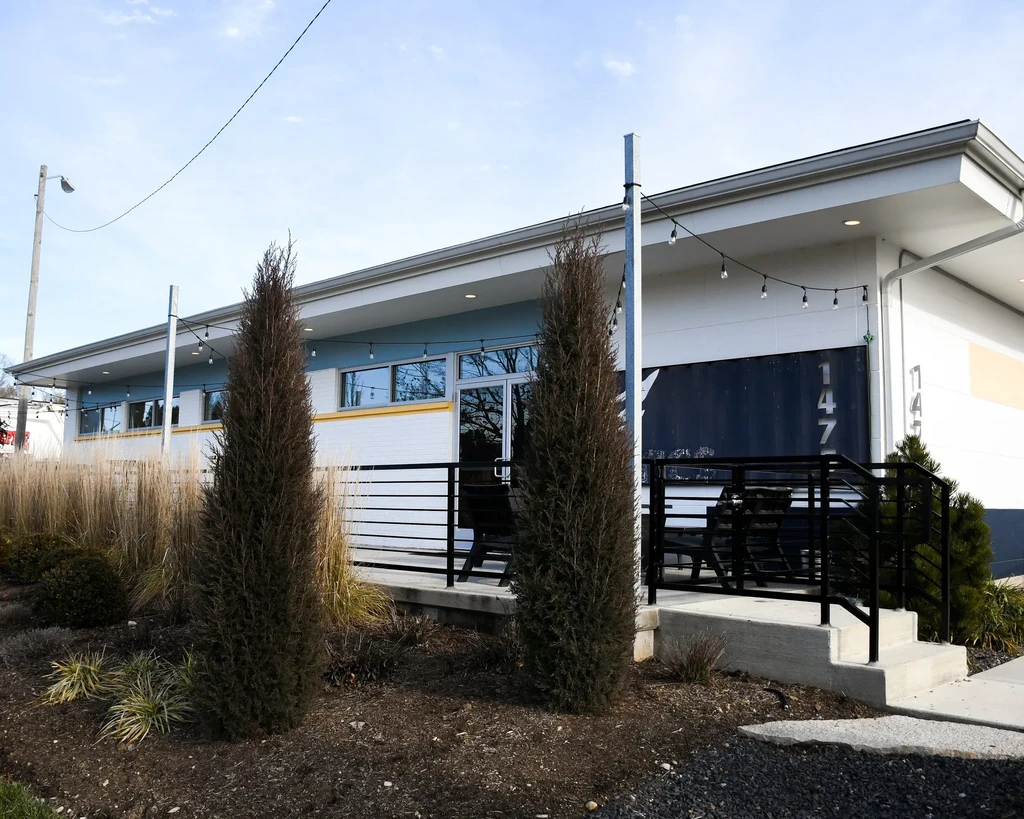 Modern light blue commercial building with large windows and outdoor patio.