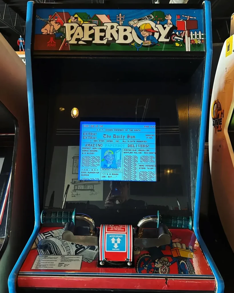 Upright Paperboy arcade game with illuminated screen and handlebars.