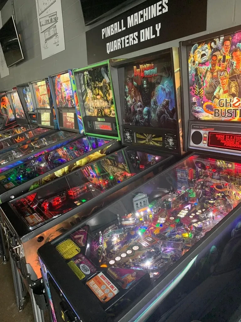 A brightly lit row of pinball machines with a 'Quarters Only' sign.