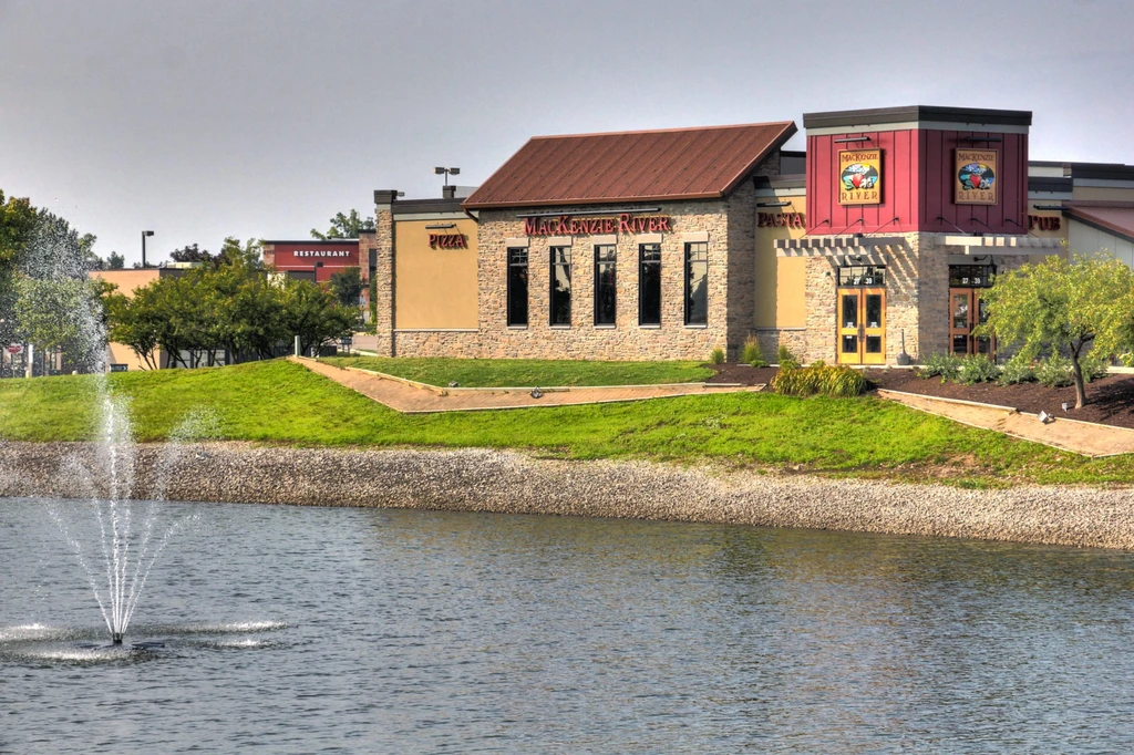 Mackenzie River restaurant across water with fountain and landscaping.