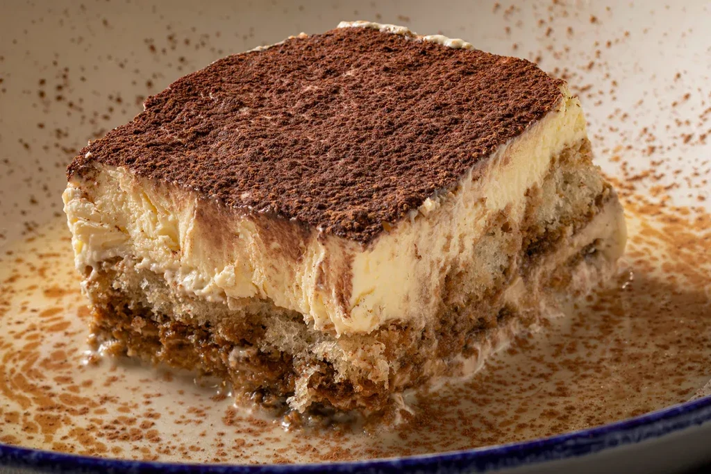 Close-up of a layered tiramisu slice dusted with cocoa powder.