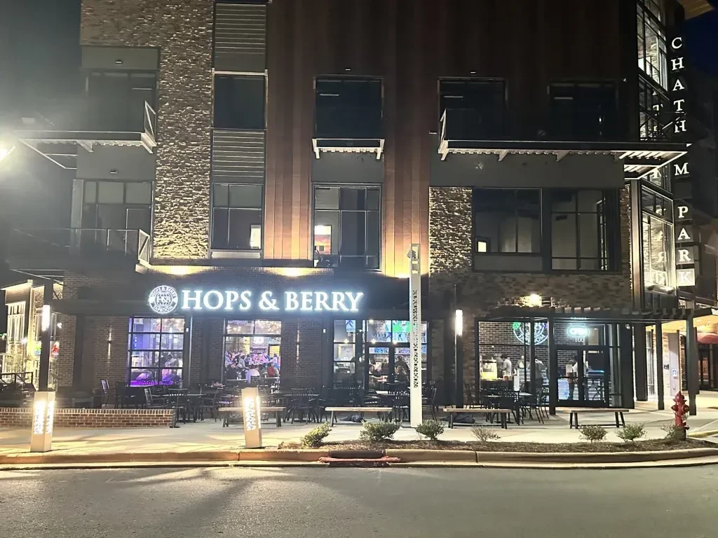 Exterior night shot of Hops & Berry restaurant in a multi-story brick building.
