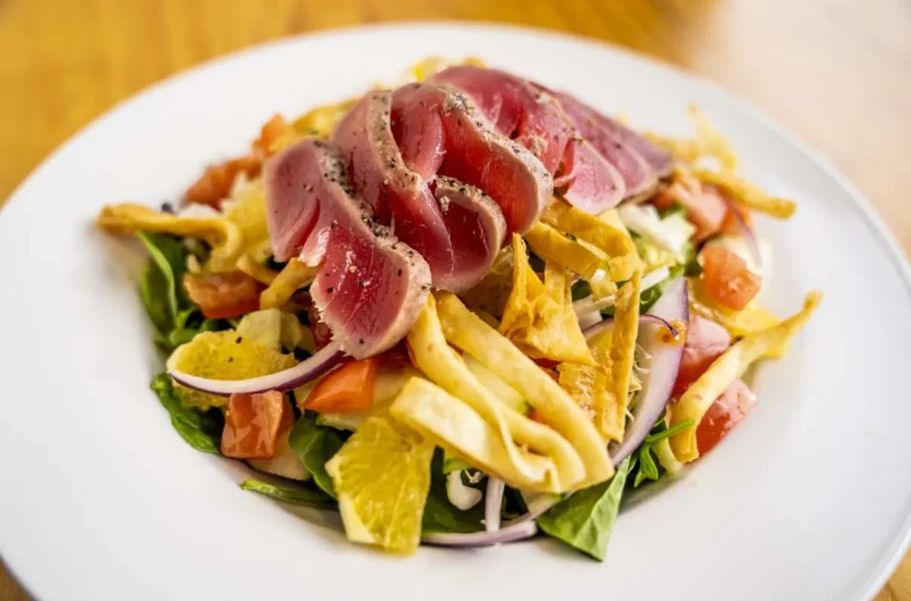 Sliced seared tuna salad with mixed greens, citrus, and crispy strips.
