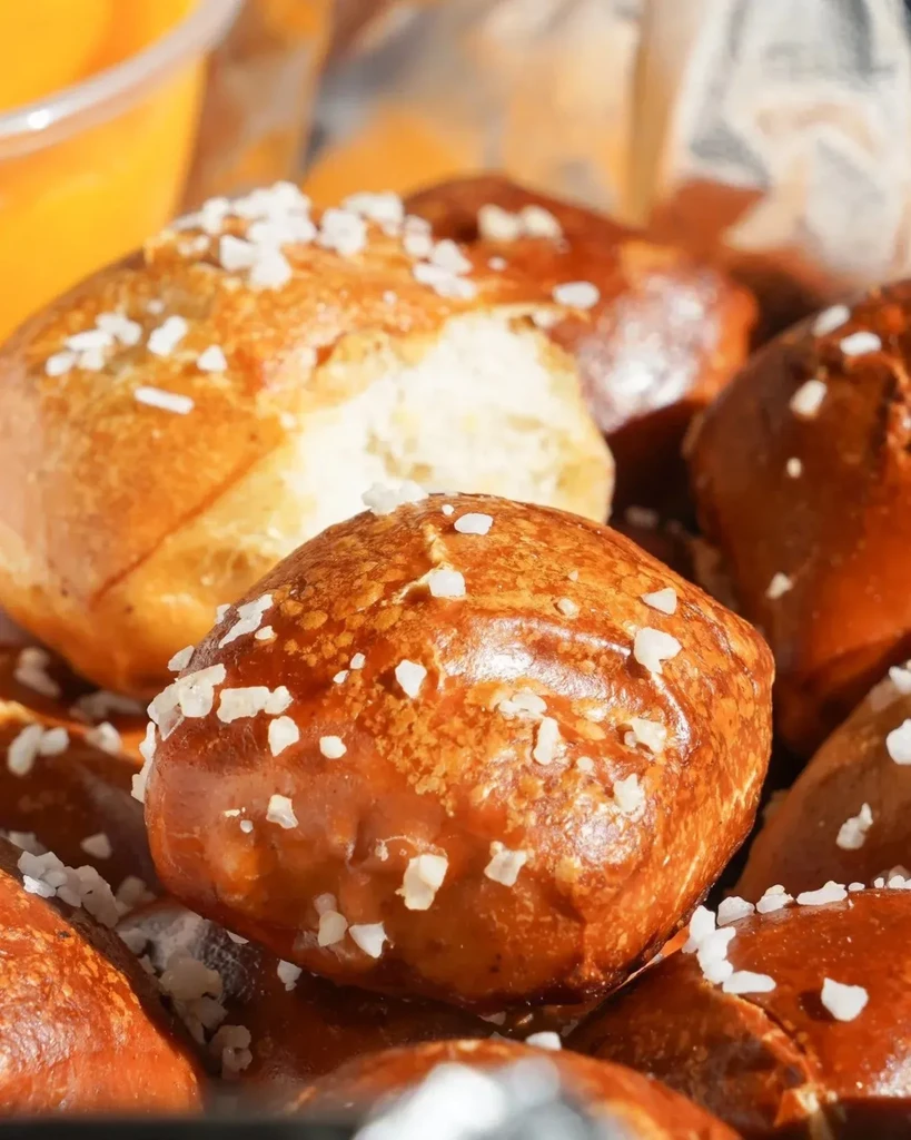 Golden-brown, salted pretzel bites with a blurred orange dip.
