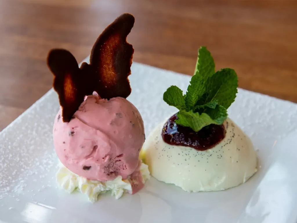 Pink ice cream with chocolate butterfly, white dome with berry compote.