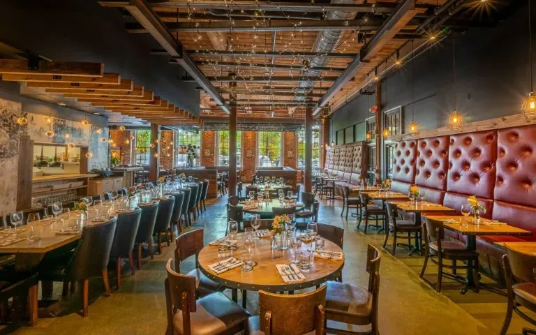 Spacious, empty restaurant with varied seating and rustic-industrial design.