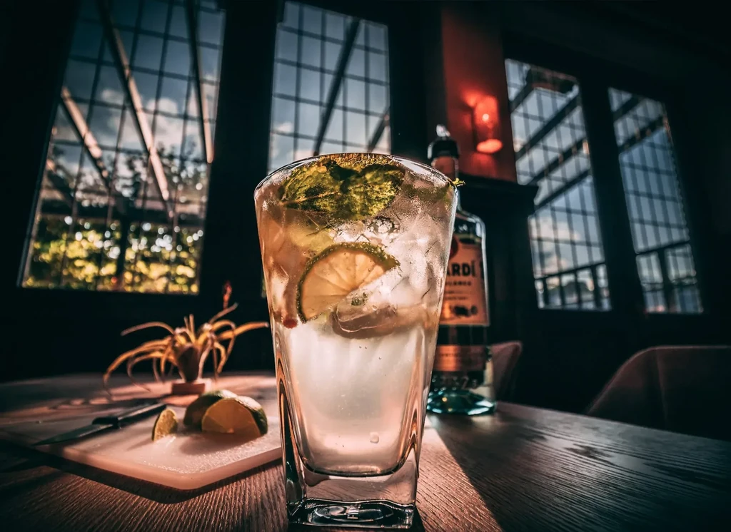 Condensation-covered cocktail with mint and lime near a Bacardi bottle.