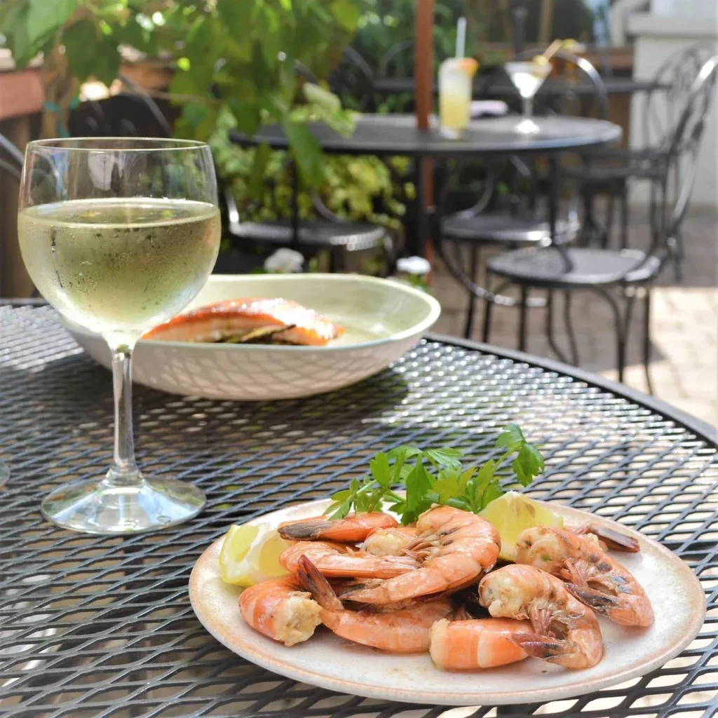 Cooked shrimp, white wine, and salmon on an outdoor restaurant table.