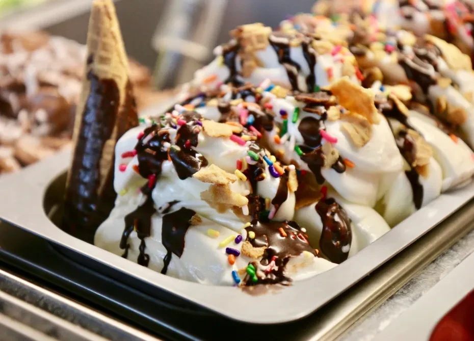 Creamy white ice cream with chocolate syrup, sprinkles, and crunchy bits.