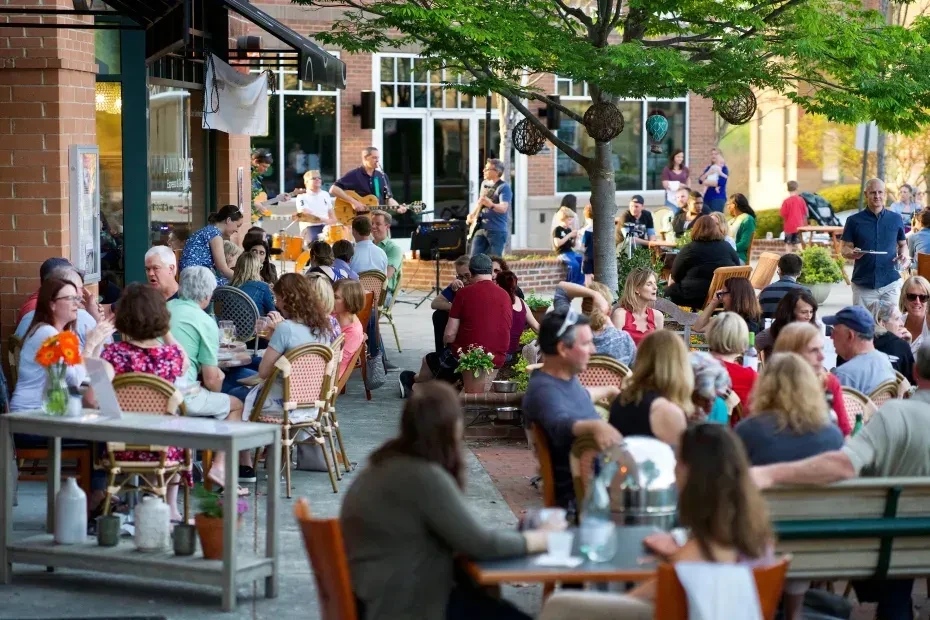 Outdoor restaurant patio full of people enjoying food and live music.