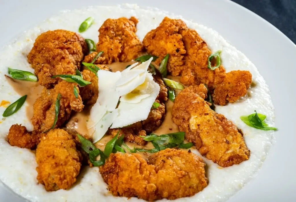 Crispy fried chicken or seafood on grits with sauce, cheese, and scallions.