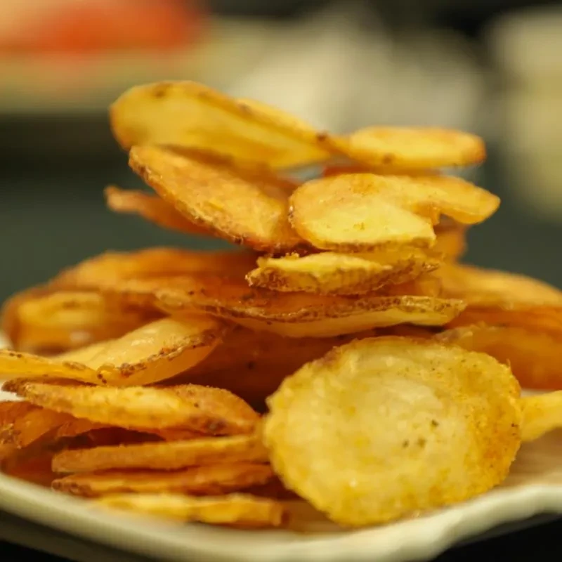 Crispy golden-brown potato chips piled high with visible seasoning.