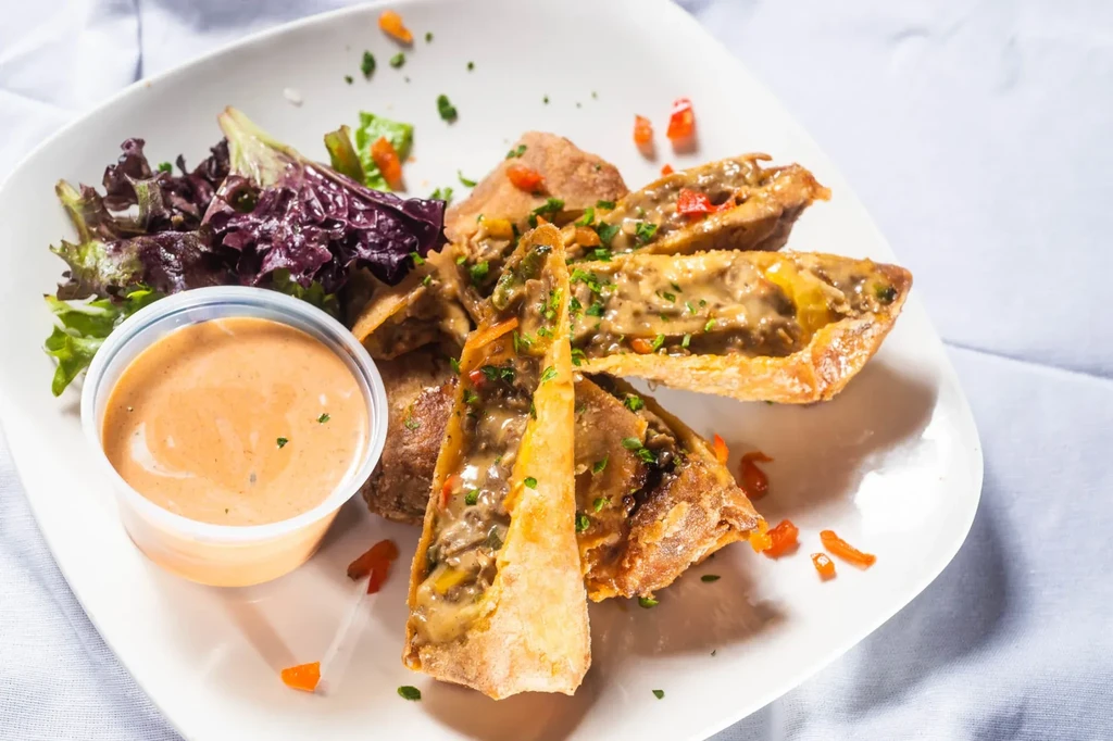 Fried pastries with meat and pepper filling, dipping sauce, and side salad.